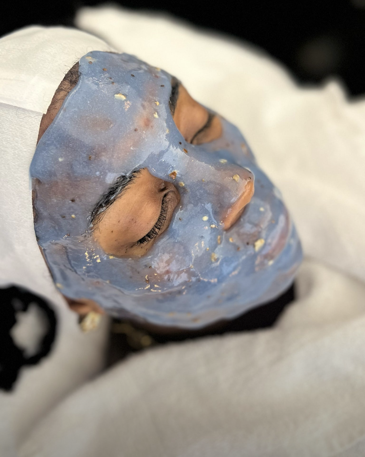 Blue HydroJelly mask setting on a client's face during a facial